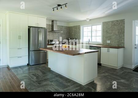 New grey and white kitchen with marble tiles, appliances and timber bench tops Stock Photo