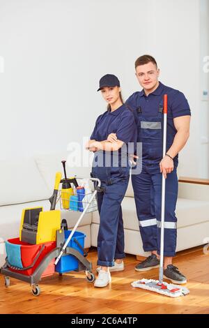 Young attractive janitors, workers of cleaning company stand posing, look at camera. Special equipment, buckets, washing rags near them. Effective, pr Stock Photo