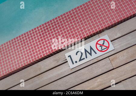 Swimming pool edge with 'No Diving 1.2 M.' warn sign. Summer recreational Stock Photo