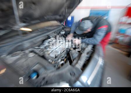 An auto mechanic works on an engine of an automobile in an auto repair shop Stock Photo