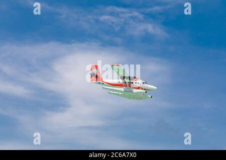 Male, Maldives - 12/17/2017: Seaplane of Trans Maldivian Airways airline is flying in blue sky over Male. Luxury travel, exotic holiday transportation Stock Photo