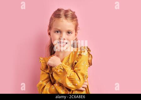 Beautiful caucasian girl 5-7 years old with pigtails wearing yellow dress look at camera. Childhood concept Stock Photo