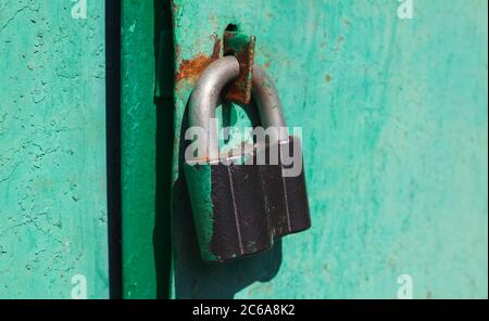 Iron lock hanging on a painted green door Stock Photo