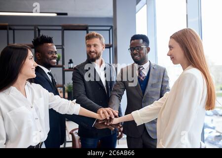 Multi-ethnic, interracial friendship, partnership concept. International group of business people joined hands together in office Stock Photo