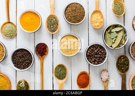 Assorted colorful spices and herbs in bowls and spoons Stock Photo
