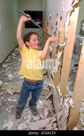 Austin Texas USA, 2003: Six-year-old boy uses crowbar to help smash drywall during remodeling project. Model Released. MR  ©Bob Daemmrich Stock Photo