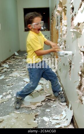 Austin Texas USA, 2003: Six-year-old boy wearing safety goggles uses a sledge hammer to help smash drywall during remodeling project. Model Released.  MR ©Bob Daemmrich Stock Photo