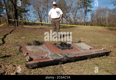 Cherokee County, Texas USA, Feb 2, 2003: County deputy stands by debris from the Space Shuttle Columbia that landed in east Texas after exploding in the skies over north central Texas early Monday morning while returning from space. All seven astronauts on board were killed in the second major shuttle disaster for NASA. ©Bob Daemmrich Stock Photo