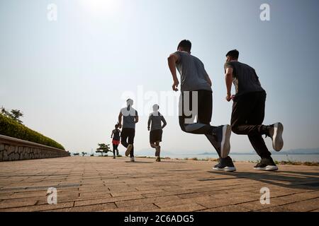 group of young asian adult men and woman running outdoors, rear and low angle view Stock Photo
