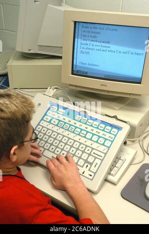 Mabank, Texas USA, September 10, 2003: Twelve-year-old boy with Hurler's Syndrome in writing class in public middle school using Intellikeys augmentative keyboard and CCTV magnifier that helps him read books his computer screen. MODEL RELEASE SP73  ©Bob Daemmrich Stock Photo