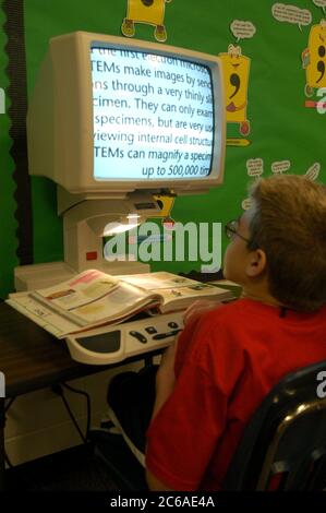 Mabank, Texas USA, September 10, 2003: Twelve-year-old boy with Hurler's Syndrome in writing class in public middle school using Intellikeys augmentative keyboard and CCTV magnifier that helps him read books his computer screen. MODEL RELEASE SP73  ©Bob Daemmrich Stock Photo