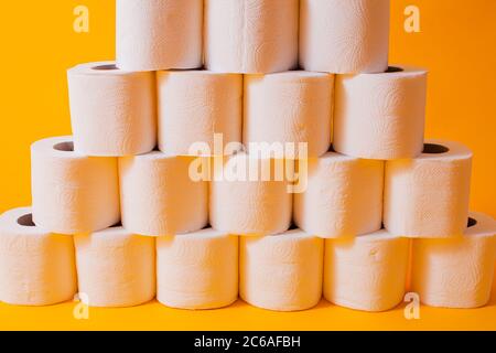 Toilet paper rolls as a wall background pattern over yellow Stock Photo