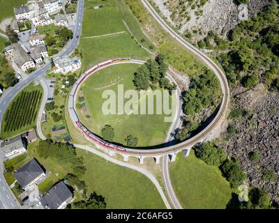 Brusio, Switzerland: 26 August 2018 - Bernina Express is going through the famous circular viaduct in Swiss Alps mountain, Brusio, Canton Grisons, Thi Stock Photo