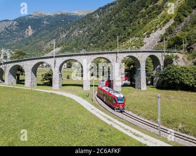 Brusio, Switzerland: 26 August 2018 - Bernina Express is going through the famous circular viaduct in Swiss Alps mountain, Brusio, Canton Grisons, Thi Stock Photo