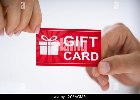 Close-up Of Person Hand Giving Gift Card To Another Person Stock Photo