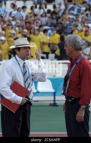 Athens, Greece September 23 2004: Greek track official (left) uses hand gestures while talking with the official starter at an evening event during track and field competition at the Athens Paralympic Games. ©Bob Daemmrich Stock Photo