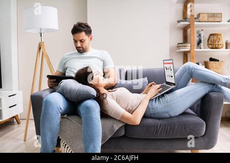 Family Couple Using Laptop And Tablet On Couch Stock Photo