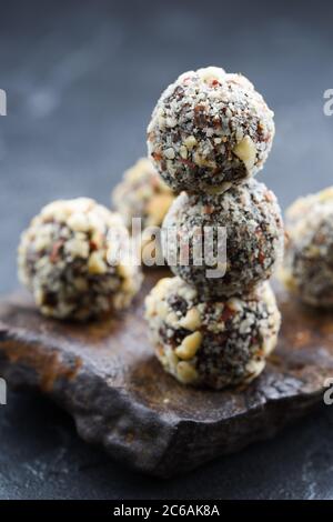 Healthy vegan snack. Homemade energy balls with hazelnuts in pile on dark stone on black background copy space vertical Stock Photo