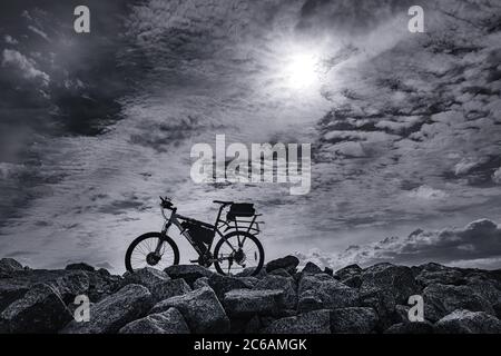 Lone electric bike against dramatic sky. Black and white image Stock Photo