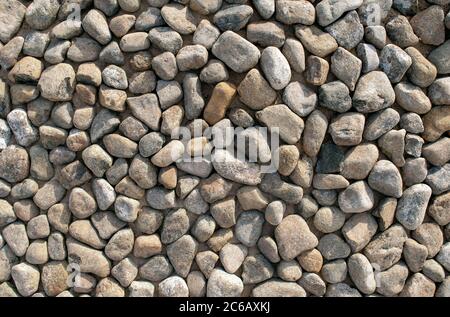 Grey dark colorful pebbles background. Top view. Backdrop made of many small round smooth sea stones. Stock Photo