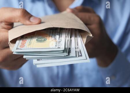 person hand putting cash in a envelope. Stock Photo