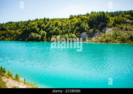 Beautiful mountain landscape - a lake with unusual turquoise water in the crater. Chalk quarry in Belarus. Sunny summer day. Stock Photo