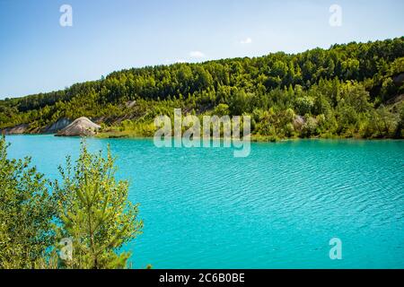 Unusual lake with turquoise water in the crater. Rocky stony shore chalk quarry in Belarus. Sunny summer day. Stock Photo