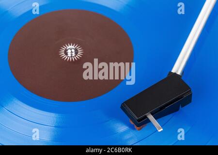 Close up of turntable cartridge on a vinyl record. Turntable playing vinyl. Needle on rotating blue vinyl. Stock Photo