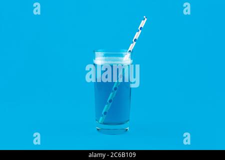 Blue lemonade with gas bubbles and a cocktail straw isolated on blue background. Blue Cocktail Drink monochrome banner with copy space. Stock Photo