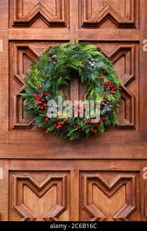 Christmas wreath on the carved wood red door Stock Photo