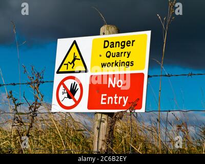 Danger Quarry Workings No Entry hazard warning sign outside a quarry with stormy sky above. Stock Photo