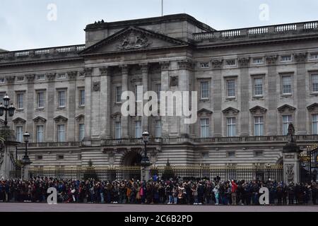 Crowds gather outside Buckingham Palace for the Changing Of The Guard Ceremony.  The imposing east facade and balcony for royal appearances.