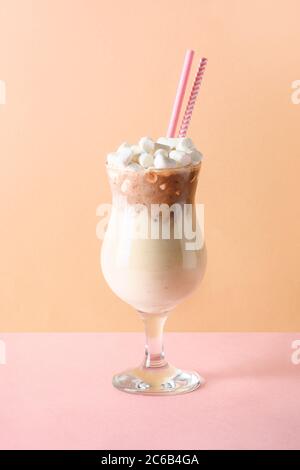 Chocolate milkshake garnish marshmallow on pink and beige paper. Stock Photo