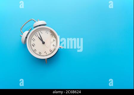 White iron alarm clock on blue background, top view, concept picture Stock Photo