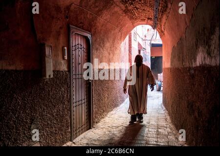 Local man dressed in traditional djellaba walking through archway in a street in the Kasbah, Marrakech, Morocco, North Africa, Africa Stock Photo