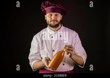 bearded male chef cook in uniform holding plastic bottle of fruit juice Stock Photo
