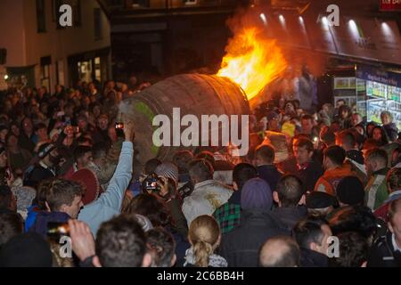 A blazing tar barrel passes through crowded streets during the annual Ottery Tar Barrel Festival, held in early November, Ottery St. Mary, Devon, Engl Stock Photo