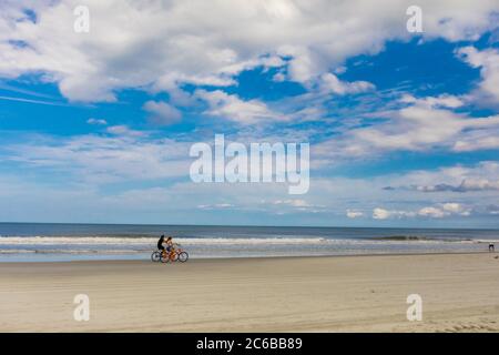 Couple bike riding on Jacksonville beach after it reopened during the Covid-19 Pandemic, Florida, United States of America, North America Stock Photo