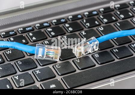 Two internet cables on a computer keyboard symbolizing connectivity issues Stock Photo