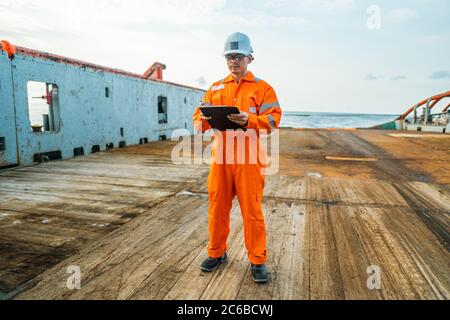 Filipino deck Officer on deck of offshore vessel or ship fills checklist. Paperwork at sea Stock Photo