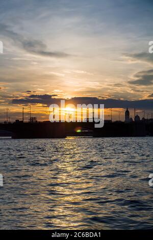 Beautiful sunset reflected in the water, city silhouette Stock Photo