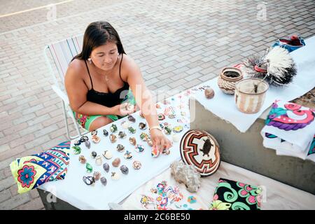 Indigenous Woman Arranging Crafts And Souvenirs At Market Stall Stock Photo