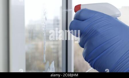 Close Up Man Hands with Protection Gloves Cleaning a Window Using Sprayed Liquid Disinfecting Against Viruses Contamination Stock Photo
