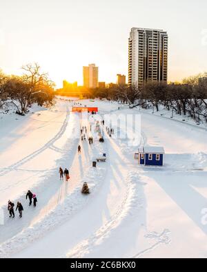 Ice skating on the Assiniboine River Trail at sunset, part of the Red River Mutual Trail, The Forks, Winnipeg, Manitoba, Canada.