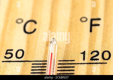 A macro shot of a classic wooden thermometer showing a temperature over 50 degrees Celsius, 122 degrees Fahrenheit. Stock Photo
