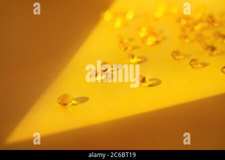 Gelatin capsules in a ray of light on a yellow background. Dietary supplement, health care, soft focus. Stock Photo