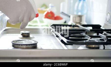 Busy Person in the Kitchen Wearing Gloves Cleans with Solution the Cooker Stove. Stock Photo