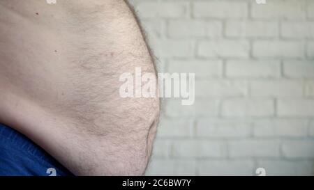 Obese Man Showing His Fat Belly, a Hungry Person Measuring His Belly Fat, Health Problems of an Old Man with Obesity Stock Photo