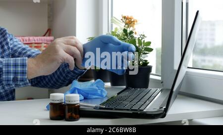 Sick Man Using a Laptop Putting on His Hands Protective Gloves, Social Distancing Lifestyle in Pandemic Period