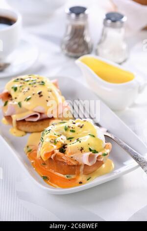Breakfast. Best Eggs Benedict - fried English bun, ham, poached eggs and delicious Hollandaise   butter sauce Stock Photo
